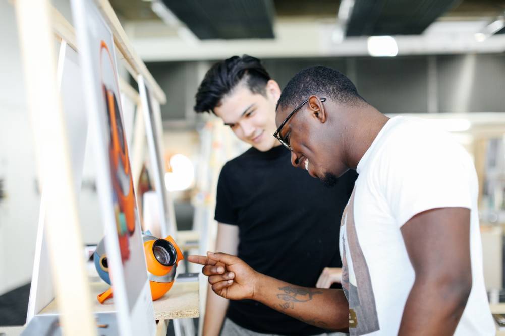 Two male students explore the work on display at an open day